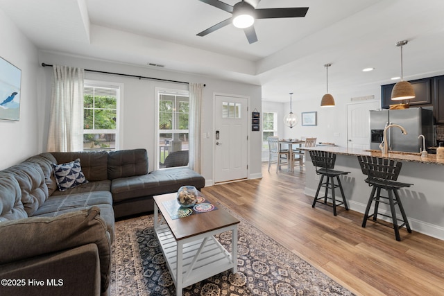 126 NW 14th St, Oak Island, NC 28465 - living area featuring light wood-style floors, a ceiling fan, a raised ceiling, and recessed lighting