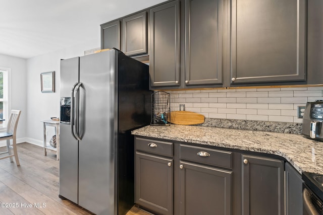 126 NW 14th St, Oak Island, NC 28465 - kitchen featuring stainless steel appliances, decorative backsplash, light wood-style flooring, and light stone counters
