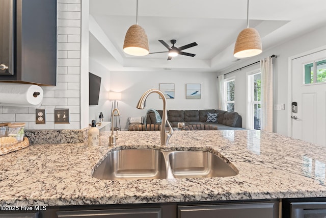126 NW 14th St, Oak Island, NC 28465 - kitchen featuring open floor plan, a tray ceiling, light stone counters, a ceiling fan, and decorative backsplash