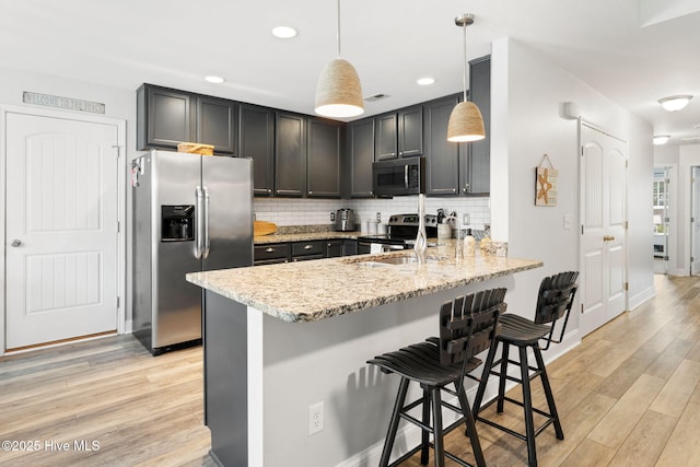 126 NW 14th St, Oak Island, NC 28465 - kitchen with stainless steel appliances, light wood-style flooring, light stone counters, backsplash, and a kitchen breakfast bar