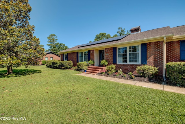 3921 Westover Rd, Wilmington, NC 28403 - ranch-style house featuring roof mounted solar panels, a front lawn, brick siding, and a chimney