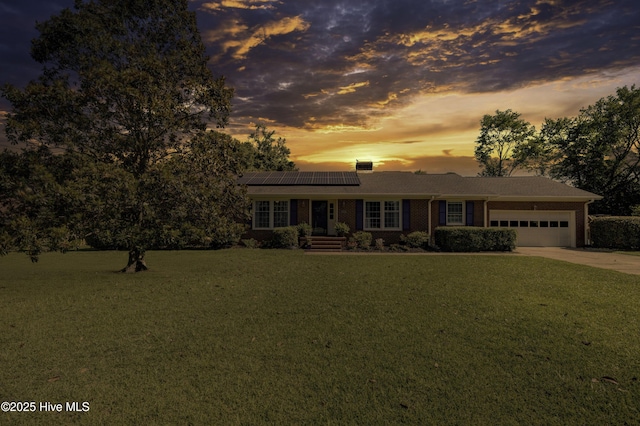 3921 Westover Rd, Wilmington, NC 28403 - view of front of house featuring a garage, a yard, solar panels, concrete driveway, and brick siding