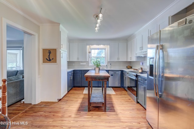 3921 Westover Rd, Wilmington, NC 28403 - kitchen with appliances with stainless steel finishes, blue cabinets, under cabinet range hood, light wood finished floors, and light countertops