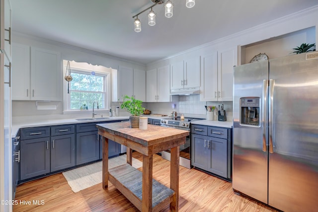 3921 Westover Rd, Wilmington, NC 28403 - kitchen with stainless steel appliances, under cabinet range hood, light wood-type flooring, light countertops, and ornamental molding