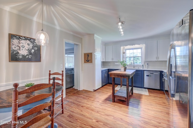 3921 Westover Rd, Wilmington, NC 28403 - kitchen with stainless steel appliances, light countertops, blue cabinets, light wood-style flooring, and crown molding