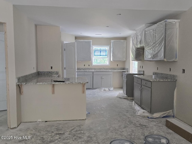 94 Osprey Watch Ln E, Oriental, NC 28571 - kitchen featuring a peninsula, a breakfast bar area, gray cabinets, and light stone countertops