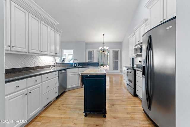 183 Baker Cir W, End, NC 27376 - kitchen featuring appliances with stainless steel finishes, a peninsula, a chandelier, decorative backsplash, and light wood-style floors