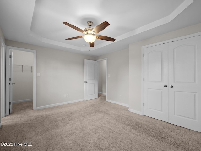 404 Bristol Ln, Hubert, NC 28539 - unfurnished bedroom featuring a tray ceiling, a closet, carpet flooring, and ceiling fan