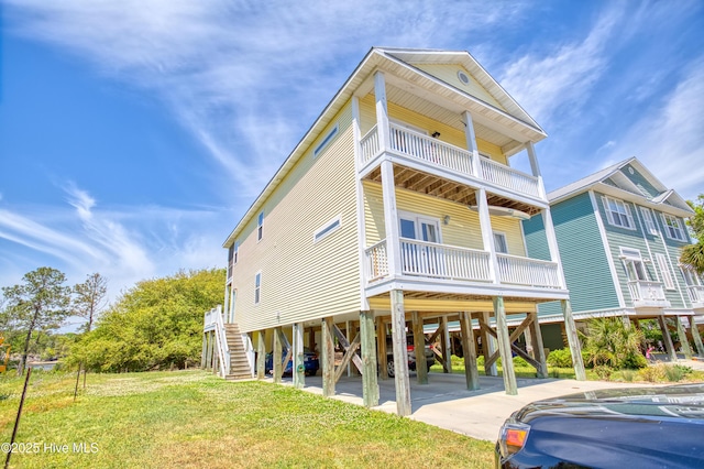 314 Spencer Farlow Dr Unit 2, Carolina Beach, NC 28428 - view of front facade featuring a carport, a balcony, stairs, and a front yard