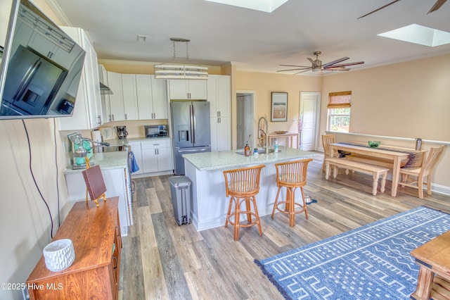 314 Spencer Farlow Dr Unit 2, Carolina Beach, NC 28428 - kitchen with stainless steel appliances, a skylight, light wood-type flooring, white cabinets, and an island with sink