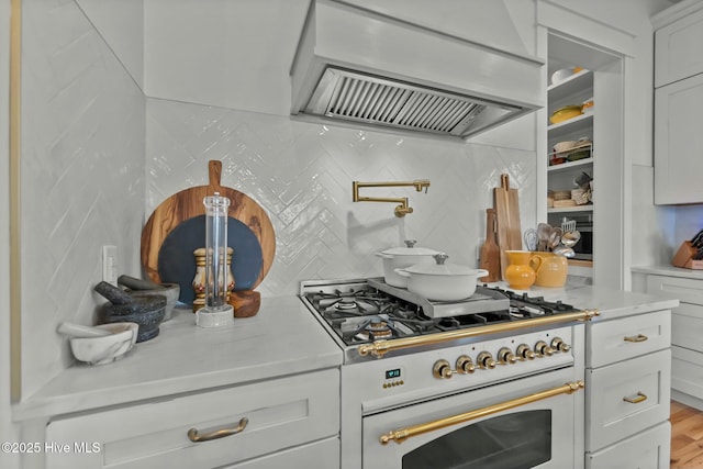 202 Topsail Watch Dr, Hampstead, NC 28443 - kitchen with custom exhaust hood, range with two ovens, light countertops, backsplash, and white cabinetry