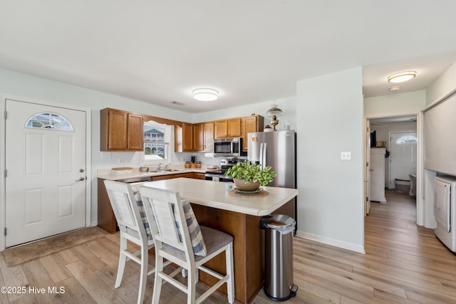 9010 W 9th St, Surf City, NC 28445 - kitchen featuring appliances with stainless steel finishes, light wood-style flooring, light countertops, a breakfast bar area, and a center island