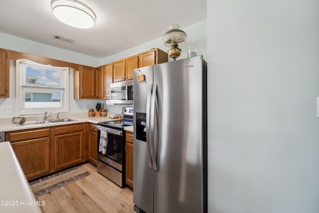 9010 W 9th St, Surf City, NC 28445 - kitchen with stainless steel appliances, light wood finished floors, light countertops, and brown cabinetry