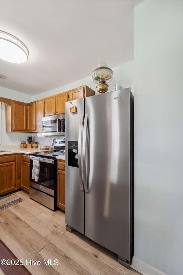 9010 W 9th St, Surf City, NC 28445 - kitchen featuring stainless steel appliances, light countertops, light wood finished floors, and brown cabinetry