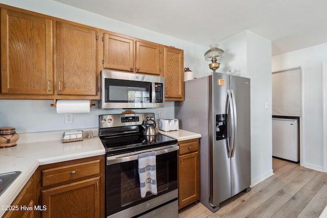 9010 W 9th St, Surf City, NC 28445 - kitchen featuring appliances with stainless steel finishes, light wood finished floors, light countertops, and brown cabinetry