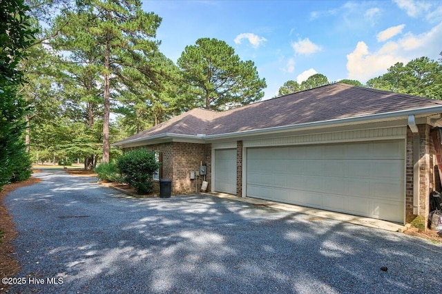 1 Pine Crest Dr, Whispering Pines, NC 28327 - view of side of property with brick siding, an attached garage, asphalt driveway, and a shingled roof