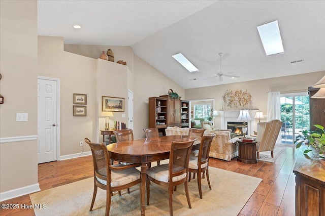 1 Pine Crest Dr, Whispering Pines, NC 28327 - dining area featuring a skylight, light wood finished floors, high vaulted ceiling, a glass covered fireplace, and a ceiling fan