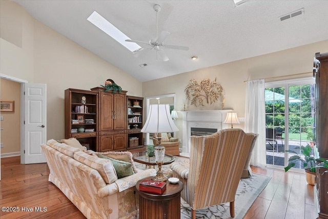 1 Pine Crest Dr, Whispering Pines, NC 28327 - living room featuring ceiling fan, light wood-style floors, high vaulted ceiling, a fireplace, and a skylight