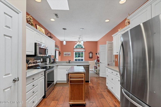 1 Pine Crest Dr, Whispering Pines, NC 28327 - kitchen with stainless steel appliances, a peninsula, ceiling fan, white cabinets, and a textured ceiling