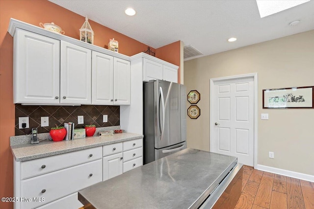 1 Pine Crest Dr, Whispering Pines, NC 28327 - kitchen featuring freestanding refrigerator, light wood finished floors, white cabinetry, decorative backsplash, and recessed lighting