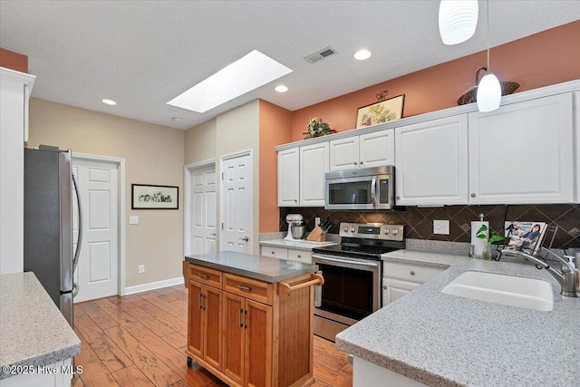 1 Pine Crest Dr, Whispering Pines, NC 28327 - kitchen with appliances with stainless steel finishes, a skylight, decorative backsplash, white cabinets, and light wood-style floors