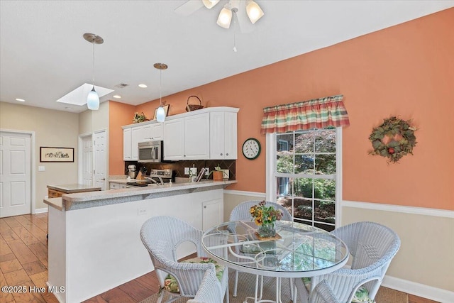1 Pine Crest Dr, Whispering Pines, NC 28327 - kitchen featuring electric range, stainless steel microwave, light wood-style floors, white cabinetry, and recessed lighting