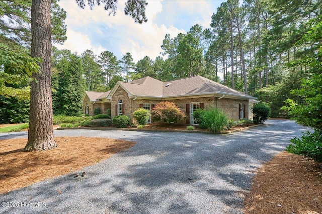 1 Pine Crest Dr, Whispering Pines, NC 28327 - view of front of house featuring curved driveway, brick siding, and a shingled roof