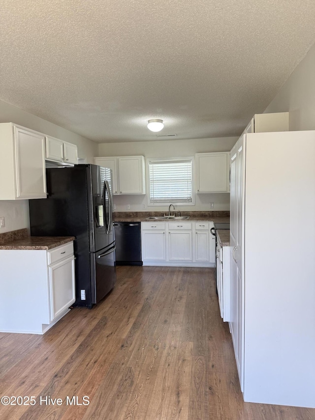 102 Harmony Way, Richlands, NC 28574 - kitchen featuring black appliances, white cabinetry, dark countertops, wood finished floors, and a textured ceiling