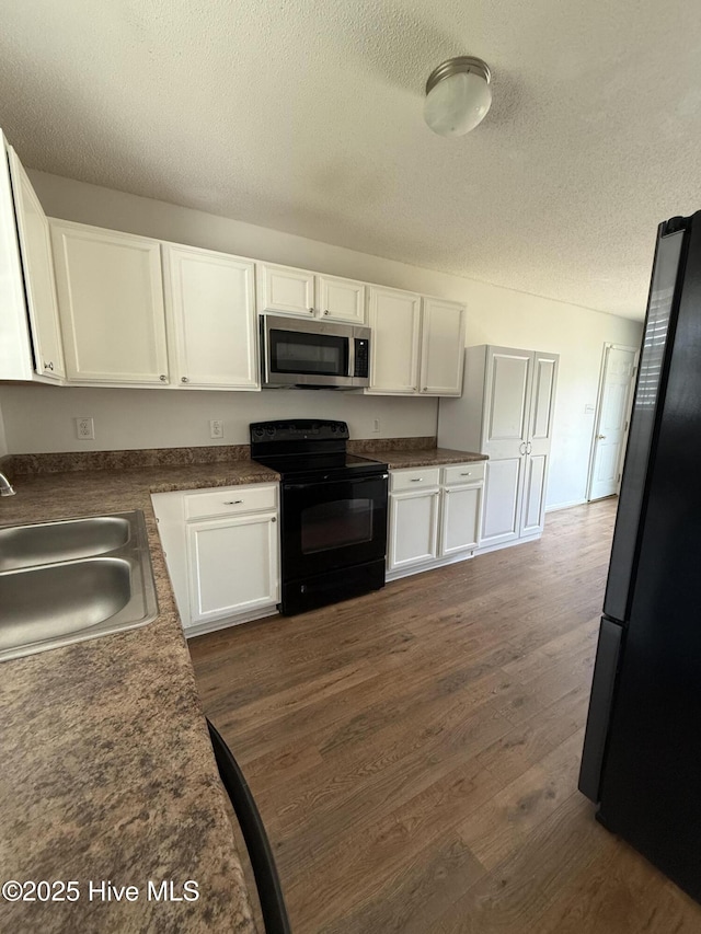 102 Harmony Way, Richlands, NC 28574 - kitchen featuring stainless steel microwave, black range with electric stovetop, freestanding refrigerator, white cabinets, and a textured ceiling