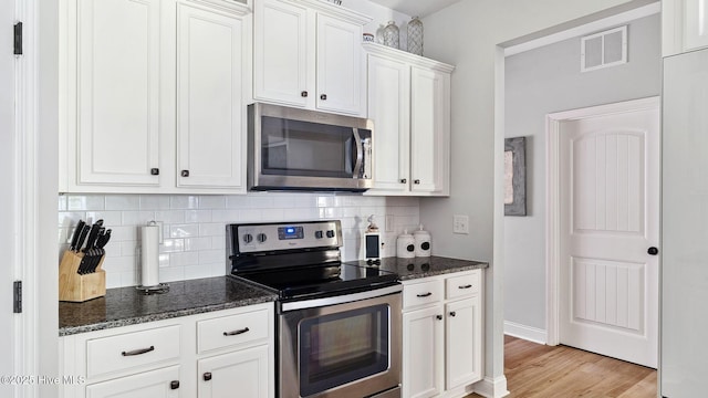 75 Bynum Ct, Vass, NC 28394 - kitchen with appliances with stainless steel finishes, tasteful backsplash, light wood-style floors, and dark stone counters