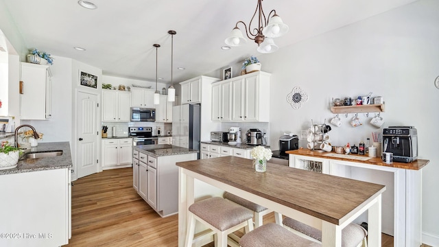 75 Bynum Ct, Vass, NC 28394 - kitchen featuring stainless steel appliances, a kitchen island, decorative backsplash, white cabinetry, and light wood-style flooring