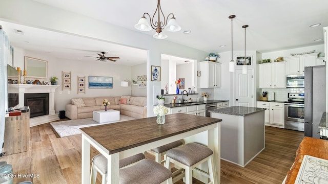 75 Bynum Ct, Vass, NC 28394 - kitchen with appliances with stainless steel finishes, a kitchen island, wood finished floors, tasteful backsplash, and recessed lighting