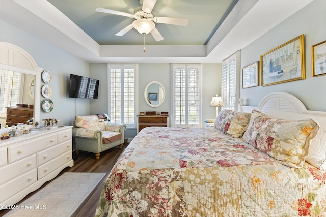 1178 Eastwood Landing Way, Sunset Beach, NC 28468 - bedroom featuring a tray ceiling, dark wood-style flooring, and a ceiling fan