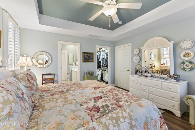 1178 Eastwood Landing Way, Sunset Beach, NC 28468 - bedroom featuring a raised ceiling, dark wood-type flooring, connected bathroom, a spacious closet, and a closet