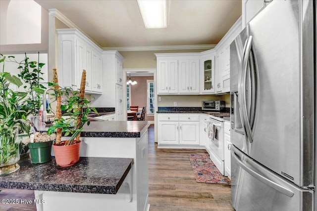 419 Morgan Trace Ln, Goldsboro, NC 27530 - kitchen with stainless steel fridge with ice dispenser, dark countertops, white range with electric stovetop, a peninsula, and wood finished floors