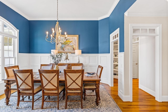 1119 Sea Bourne Way, Sunset Beach, NC 28468 - dining room with a chandelier, wood finished floors, ornamental molding, a wainscoted wall, and a decorative wall