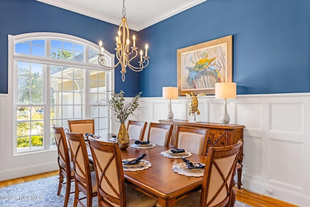 1119 Sea Bourne Way, Sunset Beach, NC 28468 - dining room featuring a chandelier, a wainscoted wall, light wood-style floors, crown molding, and a decorative wall