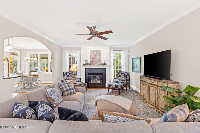 1119 Sea Bourne Way, Sunset Beach, NC 28468 - living room featuring a chandelier, crown molding, wood finished floors, arched walkways, and a ceiling fan