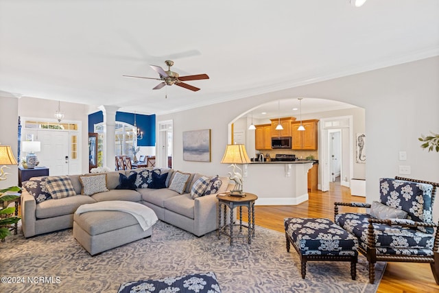 1119 Sea Bourne Way, Sunset Beach, NC 28468 - living room featuring light wood-type flooring, a ceiling fan, crown molding, arched walkways, and a chandelier