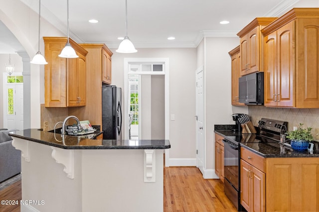 1119 Sea Bourne Way, Sunset Beach, NC 28468 - kitchen with black appliances, light wood-style floors, a peninsula, dark stone countertops, and a kitchen bar