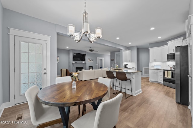 1 Miles Ct, Pinehurst, NC 28374 - dining area featuring a ceiling fan, a chandelier, light wood-type flooring, a fireplace, and recessed lighting