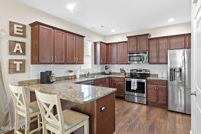 3243 Kellerton Pl, Wilmington, NC 28409 - kitchen with appliances with stainless steel finishes, a peninsula, light stone counters, and decorative backsplash