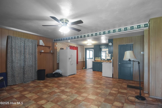 1311 Hazel Ave, New Bern, NC 28560 - kitchen with white refrigerator with ice dispenser, wooden walls, ceiling fan, stove, and blue cabinetry