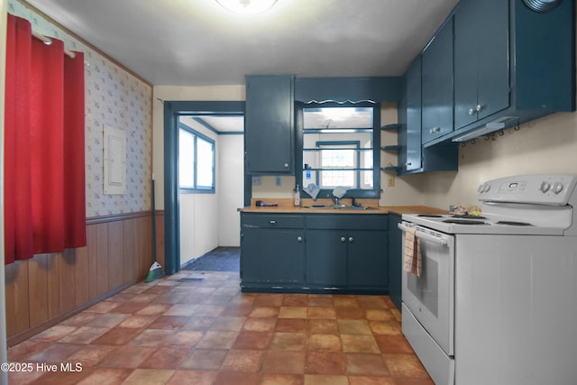 1311 Hazel Ave, New Bern, NC 28560 - kitchen featuring white electric stove, blue cabinets, a wainscoted wall, light countertops, and wallpapered walls