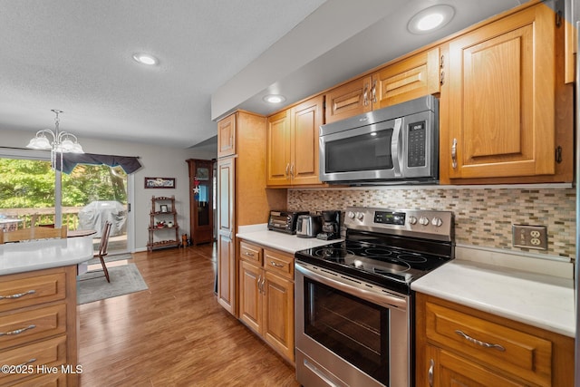 115 Baker Cir W, End, NC 27376 - kitchen featuring appliances with stainless steel finishes, a textured ceiling, a chandelier, light countertops, and backsplash