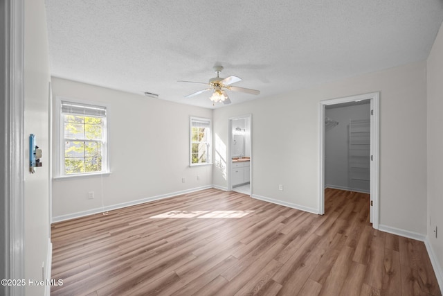 108 Bayswater Ct, New Bern, NC 28562 - unfurnished bedroom featuring a textured ceiling, a walk in closet, light wood-style flooring, a closet, and ensuite bath