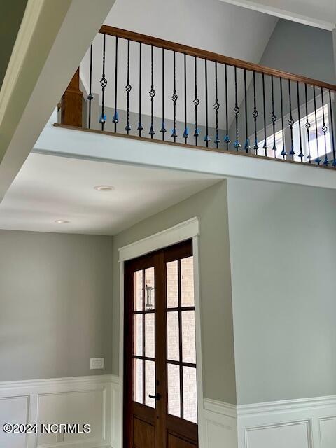 700 Bertram Ct, Hampstead, NC 28443 - staircase featuring wainscoting, a decorative wall, french doors, a towering ceiling, and recessed lighting