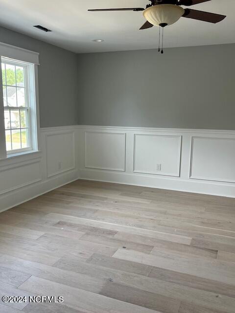 700 Bertram Ct, Hampstead, NC 28443 - spare room featuring a ceiling fan, a wainscoted wall, light wood-type flooring, and a decorative wall