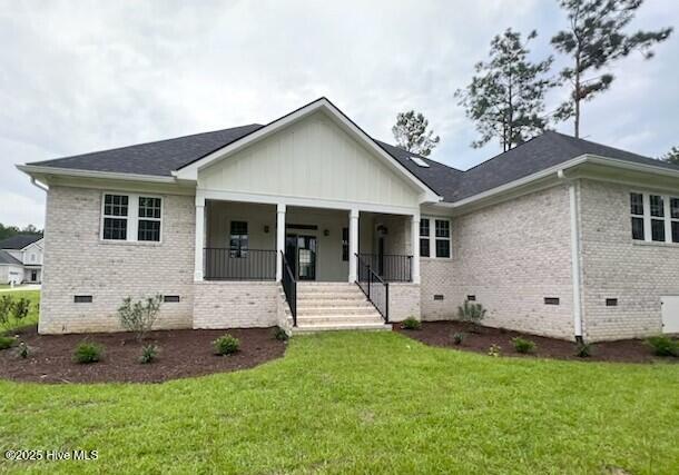 700 Bertram Ct, Hampstead, NC 28443 - view of front of property with crawl space, brick siding, board and batten siding, and a front yard