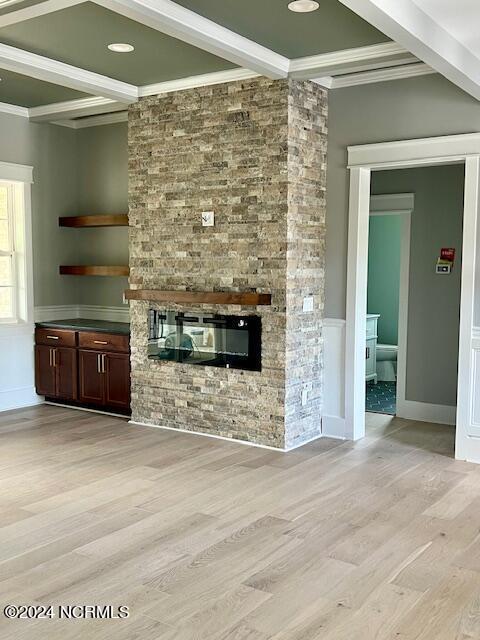 700 Bertram Ct, Hampstead, NC 28443 - unfurnished living room featuring crown molding, beam ceiling, light wood-style flooring, a fireplace, and wainscoting